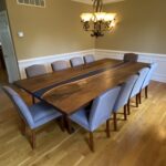 A large walnut river table for a dining room.